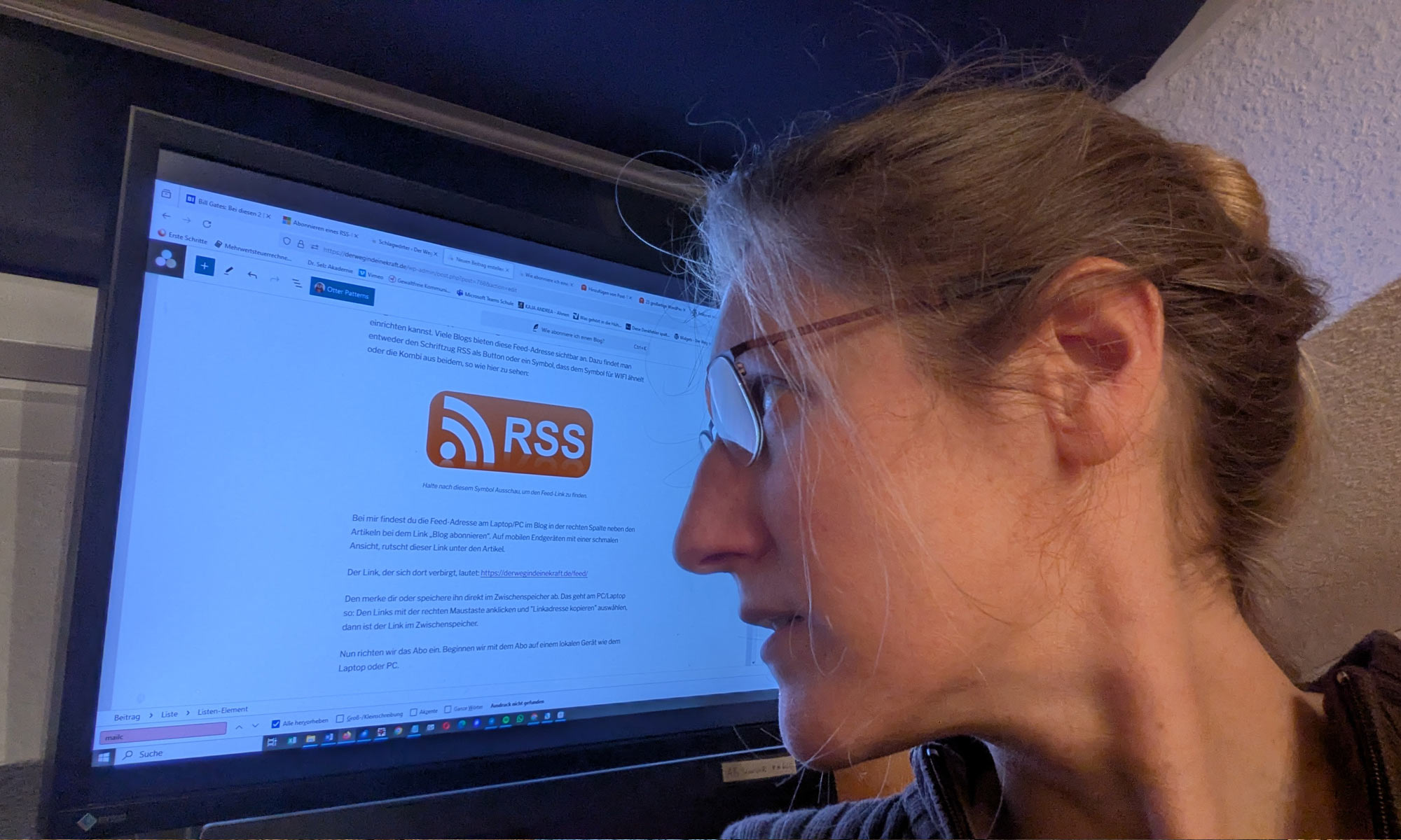 Dorothee sitzt vor dem Bildschirm ihres Computers und blickt über ihre Schulter auf das Icon RSS-Feed, was auf dem Bildschirm zu sehen ist. Foto: Dorothee Dickmann