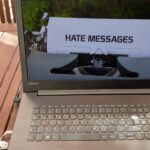 Auf einem Laptopbildschirm ist das Bild einer Schreibmaschine zu sehen, die ein Papier mit dem Wort Hate Messages eingespannt hat