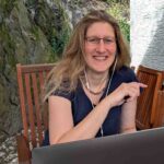 Dorothee sitzt sichtbar auf der Terrasse ihrem Laptop, zufrieden über ihren neuen Blogartikel