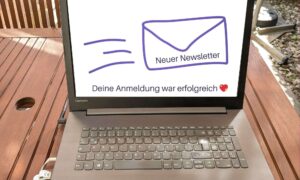 Auf dem Laptop-Bildschirm ist ein fliegender Briefumschlag zu sehen als Symbol für einen neuen Newsletter, darunter steht Deine Anmeldung war erfolgreich
