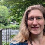 Dorothee steht am Ufer der Wupper und lächelt in die Kamera, voller Vorfreude auf das dritte Quartal und ihre To-Wants, die sie sich vorgenommen hat.