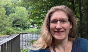 Dorothee steht am Ufer der Wupper und lächelt in die Kamera, voller Vorfreude auf das dritte Quartal und ihre To-Wants, die sie sich vorgenommen hat.