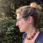 Dorothees Portrait seitlich fotografiert, wie sie am Waldrand in Richtung Sonne schaut